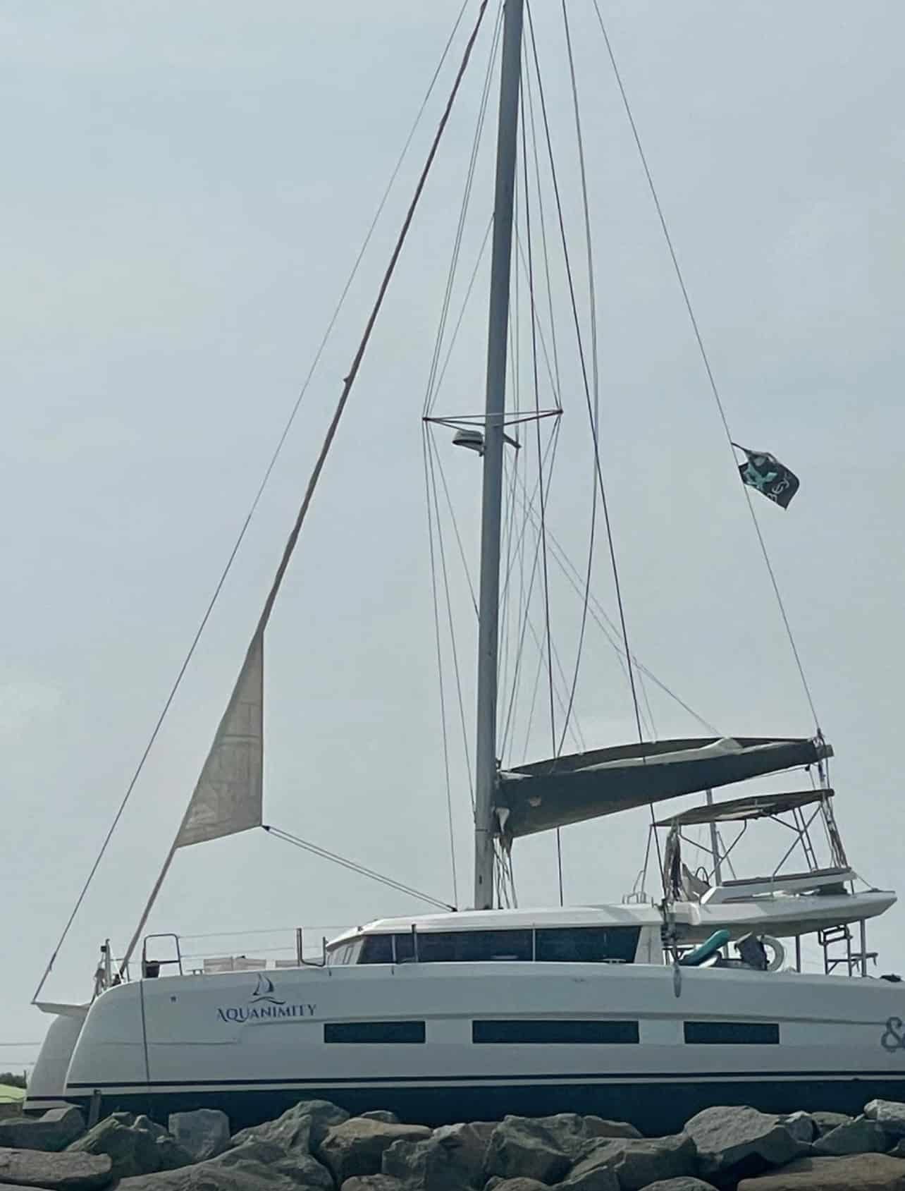 Aquanimity catamaran hull and mast, name visible on the bow, during haul-out season
